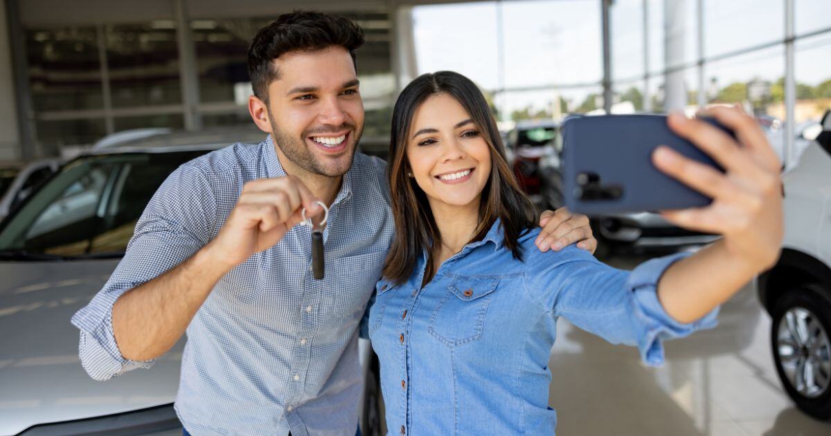 happy young couple buying car from dealership